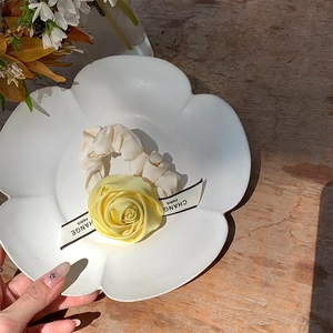 Detailed macro shot of yellow satin rose hair scrunchie with elegant ribbon on ceramic plate