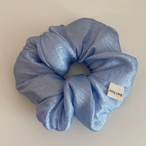 Macro detail of sky blue scrunchie showing pleated texture and Hand Made label
