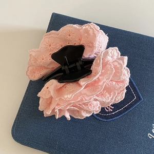 Détail de la broderie en dentelle rose et motif floral sur une élégante pince à cheveux