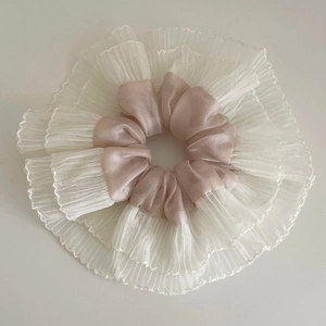 Macro view of oversized satin and lace scrunchie in pink and white pleated mesh