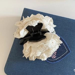 Détail d'une pince à cheveux avec rose en dentelle blanche et broderies délicates