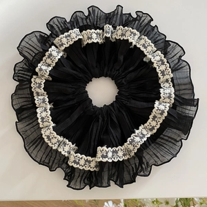 Detail of elegant black floral lace scrunchie with white embroidery and ruffled chiffon texture