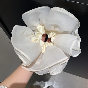 Detail of oversized white organza scrunchie with layered pleats for a voluminous look