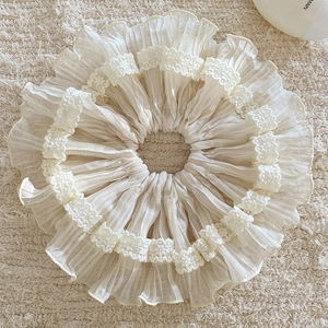 Detail view of cream-colored chiffon scrunchie with double-layered lace embroidery edges