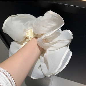 Macro shot of oversized pearl white organza scrunchie with layered floral texture
