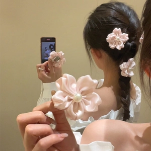 Detailansicht von rosa Satin-Blumen-Haarspangen mit Perlen getragen auf langem Haar