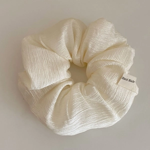 Detail of cream oversized scrunchie featuring pleated texture and Hand Made label
