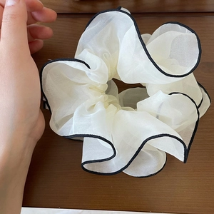 Minimalist double-layered white organza scrunchie with black trim on a wooden background