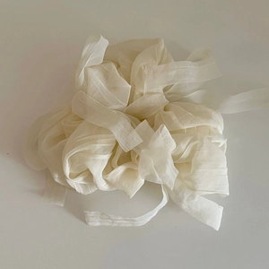 Gros plan sur un ruban de tulle translucide blanc crème avec une texture plissée élégante