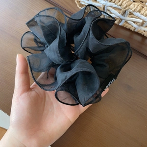 Close-up of black double-layered mesh scrunchie with Fashion label on sheer organza fabric
