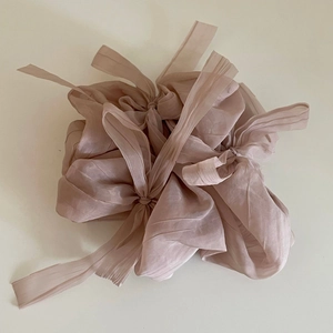 Détail du chouchou plissé en mousseline rose poudré avec de longs rubans fluides et soyeux