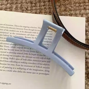 Détail d'une pince à cheveux bleu clair mat avec un mécanisme à ressort doré