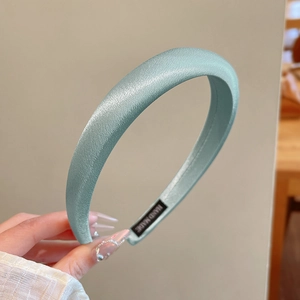 Detailed shot of mint green satin padded headband featuring a handmade inner label
