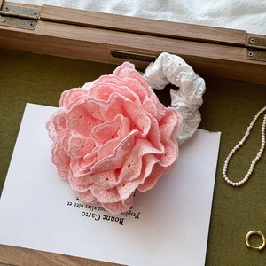 Detail of pink floral scrunchie with intricate embroidery and white lace edges