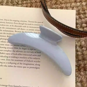 Détail d'une pince à cheveux en résine bleu clair brillante posée sur une page de livre