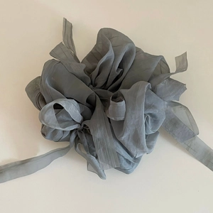 Détail d'un chouchou en organza gris avec nœud plissé et longs rubans fluides