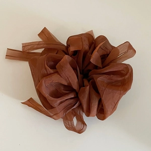 Détail d'un chouchou géant marron foncé avec texture en tissu plissé multicouche