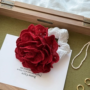 Close-up of red rose hair scrunchie with intricate floral embroidery and lace texture