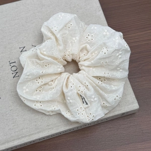 Dettaglio del ricamo traforato bianco su un elastico per capelli in stile retrò francese