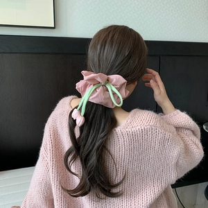 Detail of pink tulip scrunchie on low ponytail, showing floral charms and pleated fabric