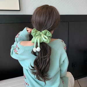 Detail of mint green scrunchie with bow and flower buds on a low ponytail