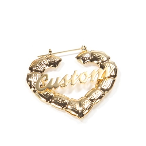 Détail macro d'une boucle d'oreille cœur bambou dorée avec texte personnalisé