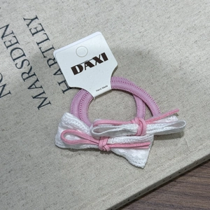 Détail d'un élastique à cheveux rose avec dentelle et nœud sur carte DAXI