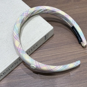 Détail d'un serre-tête en tissu à carreaux violets avec un bouton décoratif fait à la main