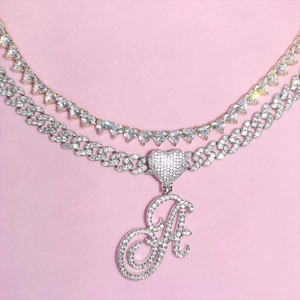 Detail of luxury iced out heart tennis chain and script letter A Cuban link necklace