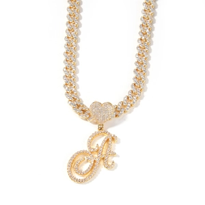 Macro detail of iced-out gold Cuban link necklace with heart and script letter A pendant