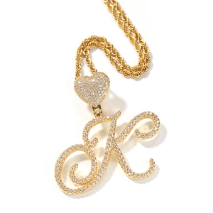 Macro detail of gold-plated cursive letter K pendant with zircon heart clasp and rope chain