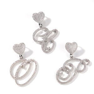 Detail view of heart-shaped studs with crystal-encrusted cursive letter charms O G P