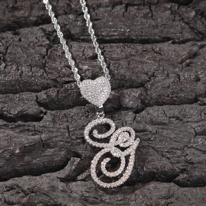 Detailed macro of silver iced-out letter G pendant with heart clasp on rope chain