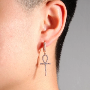 Gros plan de boucles d'oreilles croix d'Ankh en or rose serties de zircons clairs