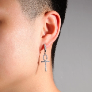 Gros plan d'une boucle d'oreille croix Ankh style hip hop avec zircons blancs brillants