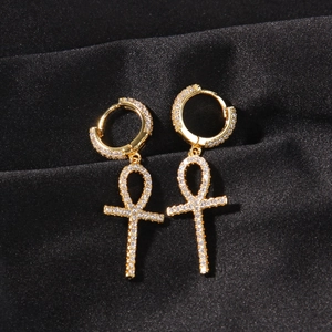 Gros plan sur les boucles d'oreilles Ankh dorées avec cristaux blancs sur satin noir