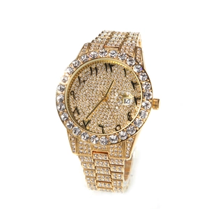 Macro view of gold quartz watch with iced-out crystals and Arabic numeral dial details