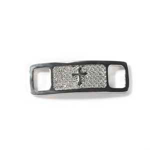 Detailed view of silver shoe lace charm with inlaid zircon stones and cross emblem