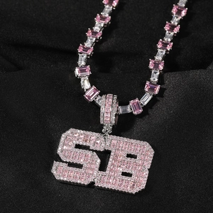 Macro shot of hip-hop necklace with pink zircon SB letter pendant on black silk