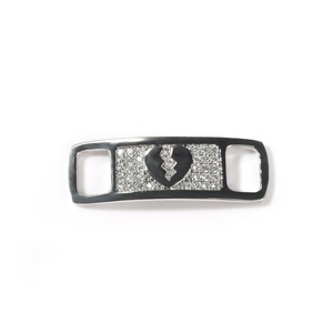 Macro detail of silver shoe charm with broken heart design and shiny clear zircon stones