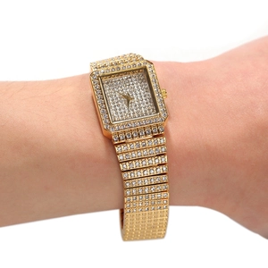 Gros plan d'une montre à quartz carrée dorée avec cristaux luxueux sur le poignet