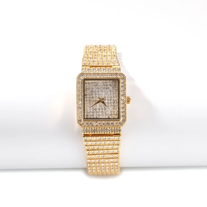 Détail macro d'une montre à quartz carrée de luxe avec pavage complet de cristaux dorés