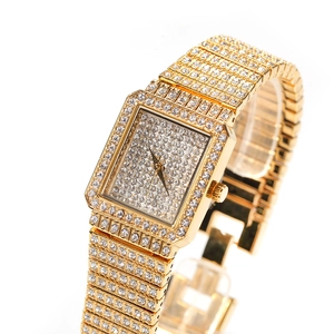 Gros plan d'une montre carrée dorée pour femme ornée de cristaux et bracelet métallique