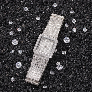 Détail macro d'une montre carrée argentée de luxe sertie de diamants sur des pierres noires