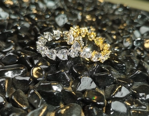 Macro shot of gold and silver heart-shaped cubic zirconia rings on black stones