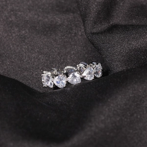 Macro close-up of heart-shaped cubic zirconia row set in polished silver band