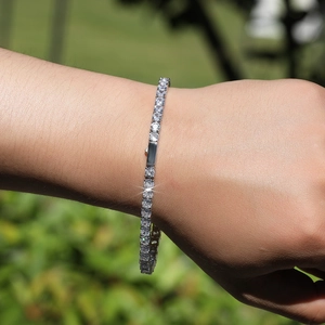 Detailopname van een zilveren tennisarmband met 4mm zirkonia stenen om een menselijke pols