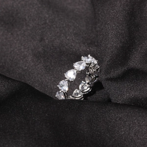 Macro shot of a heart-shaped zircon row ring on black silk background