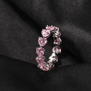 Close-up of heart-cut pink zircon stones on a silver band over black silk background