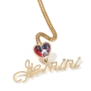 Detail view of a gold heart photo locket with pave-set crystals and Gemini script pendant